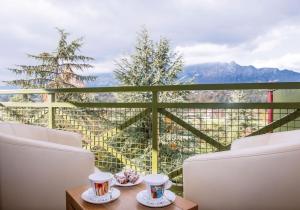 un balcón con 2 sillas y una mesa con tazas. en Hotel *** & Spa Vacances Bleues Villa Marlioz, en Aix-les-Bains