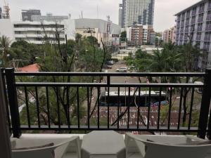 a balcony with chairs and a view of a city at The Avenue Residences in Pattaya