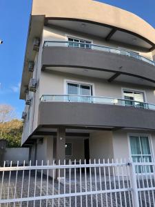 une clôture blanche devant un bâtiment dans l'établissement Bombinhas Residencial Ecomar, à Bombinhas