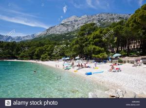 people on a beach with mountains in the background at Ema in Brela