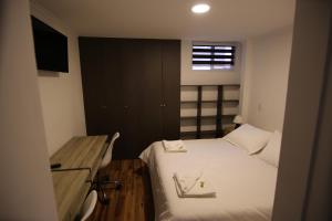 Habitación pequeña con cama y escritorio. en Aparthotel Don Alonso, en Antofagasta