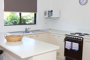 a white kitchen with a stove and a sink at Noosa Sound Resort Noosaville in Noosaville