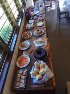 uma longa mesa cheia de diferentes tipos de alimentos em Pousada Viajantes do Tempo em Cunha