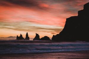 a sunset on the beach with rocks in the ocean at Hótel Kría in Vík