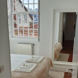 a mirror with two towels on a bed with a window at Lux Ribeira - ALL INCLUDED in Porto