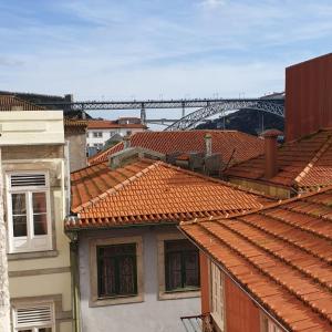 uma vista para os telhados de edifícios com uma ponte ao fundo em Lux Ribeira - ALL INCLUDED em Porto