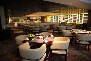a restaurant with tables and white chairs and a bar at Shanghai Hongqiao Airport Hotel - Air China in Shanghai