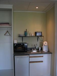 a small kitchen with a microwave and a sink at McBayne House in Hamilton