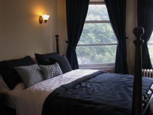 a bedroom with a bed and a window with curtains at McBayne House in Hamilton