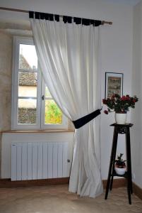 a white curtain in a room with a window at Les Cimaises du Couvent in Beaune