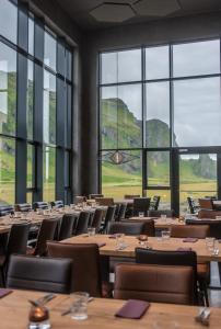 a large room with tables and chairs and windows at Hótel Kría in Vík