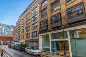 een rij gebouwen in een stadsstraat met geparkeerde auto's bij 2 Bed Executive Apartment next to Liverpool Street FREE WIFI by City Stay Aparts London in Londen