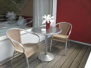 einen Glastisch mit zwei Stühlen und eine Vase mit Blumen in der Unterkunft Haus Mariandl in Düsseldorf