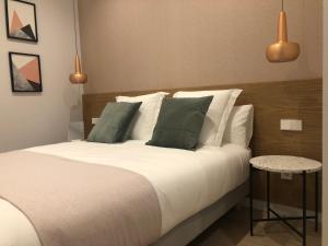 1 dormitorio con 1 cama con sábanas blancas y almohadas verdes en MARCIAL SUITE Central, modern and NEW., en San Sebastián