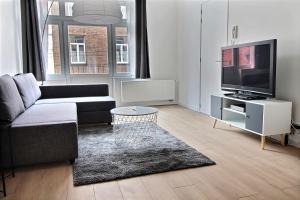 sala de estar con sofá y TV de pantalla plana en Rent a Flat - Bruxelles, en Bruselas