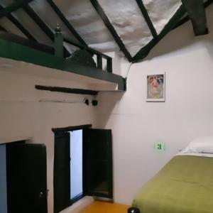 1 dormitorio con 1 cama y 1 litera verde en Cedron Hostel, en Bogotá