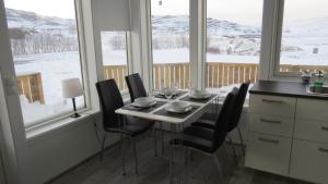 a dining room table with black chairs in front of windows at Hvammur 2 Bjarg with private hot tub in Drangsnes