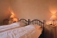 two beds in a bedroom with two lamps on tables at Hotel Grüner Jäger in Jesteburg