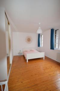 a white bedroom with a bed and a wooden floor at La Cotonnerie in Saint-Quentin