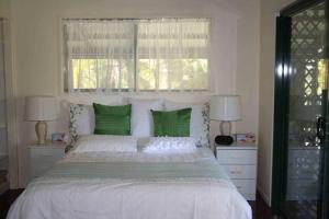 a bedroom with a large white bed with green pillows at True North B&B in Horseshoe Bay