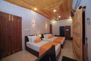 two beds in a room with wooden ceilings at King Reach in Anuradhapura