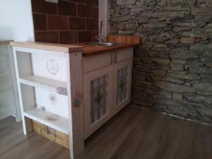 a kitchen with a sink and a stone wall at Pokojíky na Větrné in Malšín +27 photos