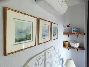 a hallway with four pictures on a wall with a chair at La Casetta in Mortola Inferiore