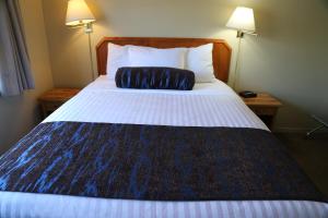 uma cama grande num quarto de hotel com uma almofada em Slumber Lodge em Penticton