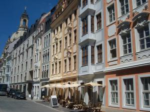 a row of buildings with tables and umbrellas on a street at Historisches Bürgerhaus Dresden -Kulturstiftung- in Dresden