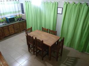 cocina con mesa de madera, sillas y cortinas verdes en Balcones de Molinari en Cosquín