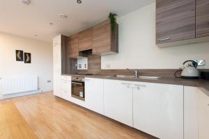 a kitchen with white cabinets and a wooden floor at City Living Apartments in London