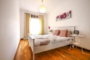 a bedroom with a white bed and a window at Apartamento Tejo in Cacilhas