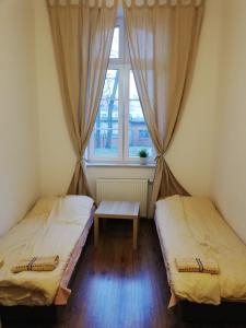 two beds in a room with a window and a table at Apartament Parkowy in Kętrzyn