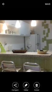 a kitchen with a counter with chairs and a refrigerator at Ap aluguel no Guaibim in Guaibim