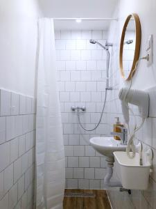 W białej łazience znajduje się umywalka i lustro. w obiekcie Chesscom Guesthouse w Budapeszcie