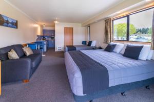 um quarto com uma cama grande e um sofá em Lakeside Motel & Apartments em Te Anau
