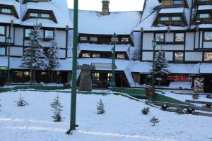 a building covered in snow with a courtyard with trees at Kopaonik011 Konaci Apartments in Kopaonik