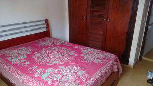 1 dormitorio con 1 cama rosa y armario de madera en Apto Guarapari - Praia do Morro - 50 m da praia, en Guarapari