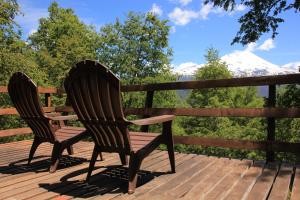 two chairs sitting on a deck with mountains in the background at Conguillio Cabaña Chercan in Conguillío