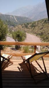 a bench sitting on a porch with a view of a river at Cabañas Emporio de la Meme in San José de Maipo