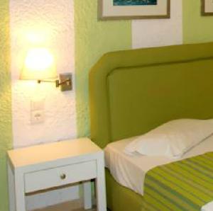 a bedroom with a bed and a nightstand with a lamp at Perla Apartments in Agia Pelagia