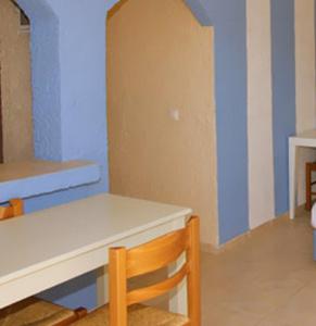 a dining room with a white table and a chair at Perla Apartments in Agia Pelagia