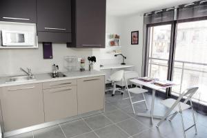 a kitchen with white cabinets and a table and chairs at Le Campus Appartement in Nice +14 photos