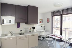 a kitchen with white cabinets and a table with chairs at Le Campus Appartement in Nice