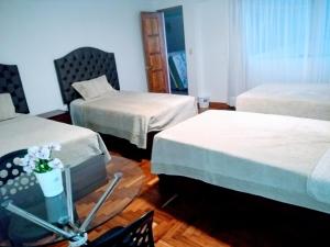 Habitación con 2 camas y mesa con TV. en Residencial Belle Maison, en Cusco