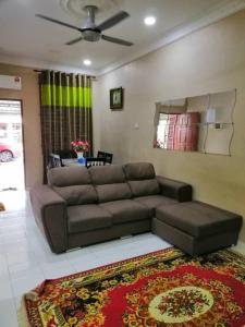 ein Wohnzimmer mit einem braunen Sofa und einem Teppich in der Unterkunft KhainadzMuslim Homestay in Malakka