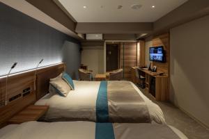 高山市にあるワットホテル&スパ飛騨高山のベッドとテレビが備わるホテルルームです。