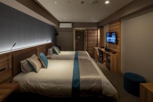 a hotel room with two beds and a television at Wat Hotel & Spa Hida Takayama in Takayama
