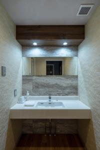 a bathroom with a sink and a large mirror at Wat Hotel & Spa Hida Takayama in Takayama