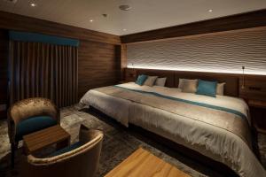 a bedroom with a large bed and a chair at Wat Hotel & Spa Hida Takayama in Takayama